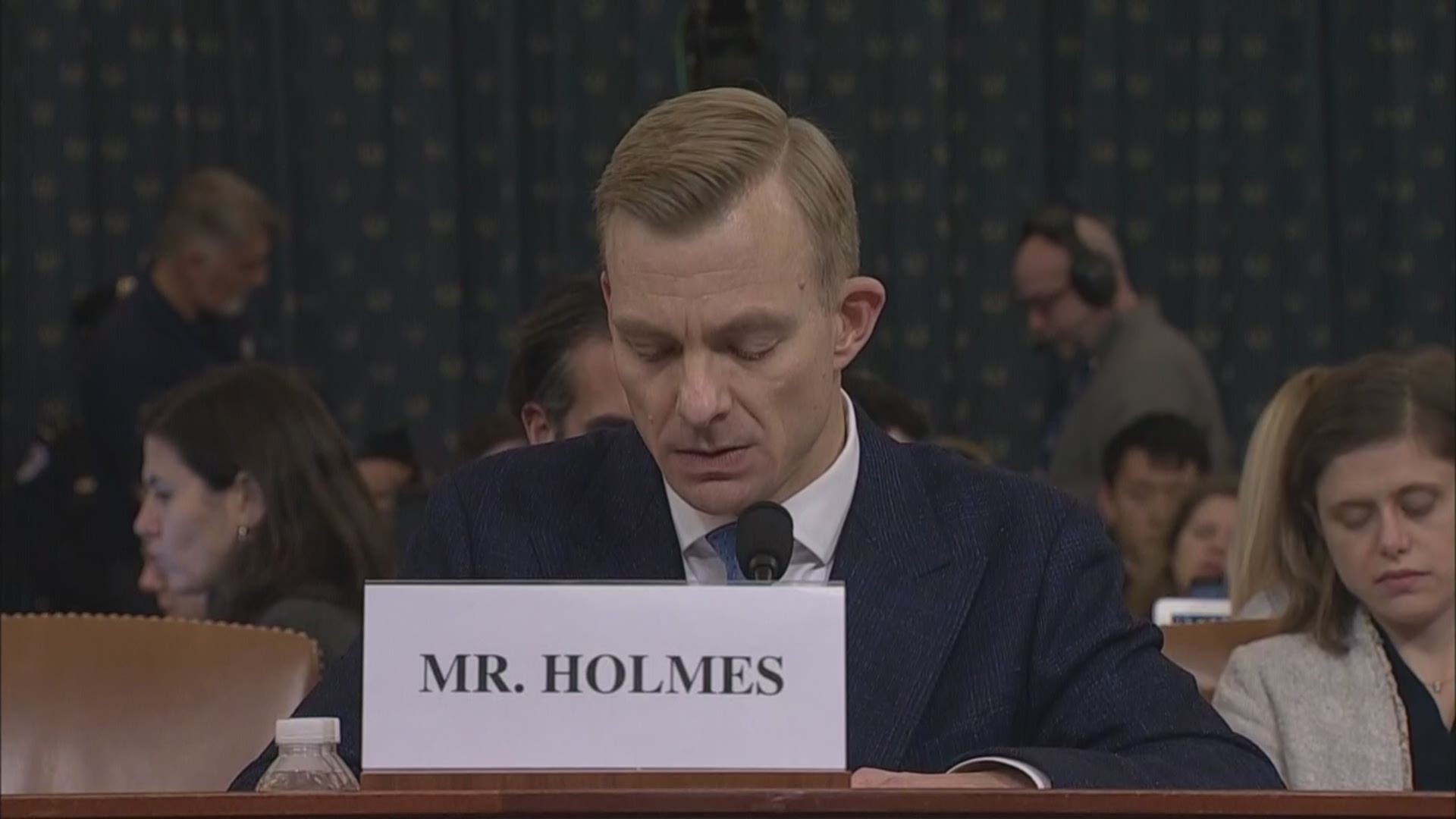 Holmes says he was at lunch with Ambassador Gordon Sondland when he overheard him talking with President Trump about the Ukrainian president.