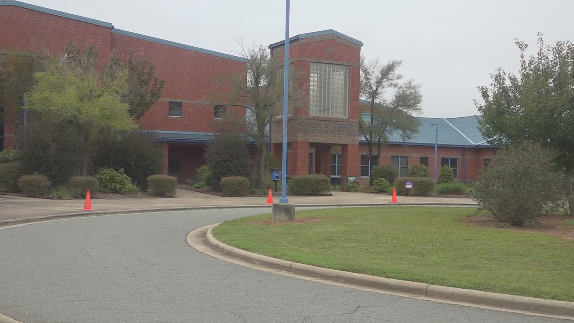 Alamance-Burlington Schools officials said an incident between two parents in the car rider line at Garrett Elementary led to one of them being charged.