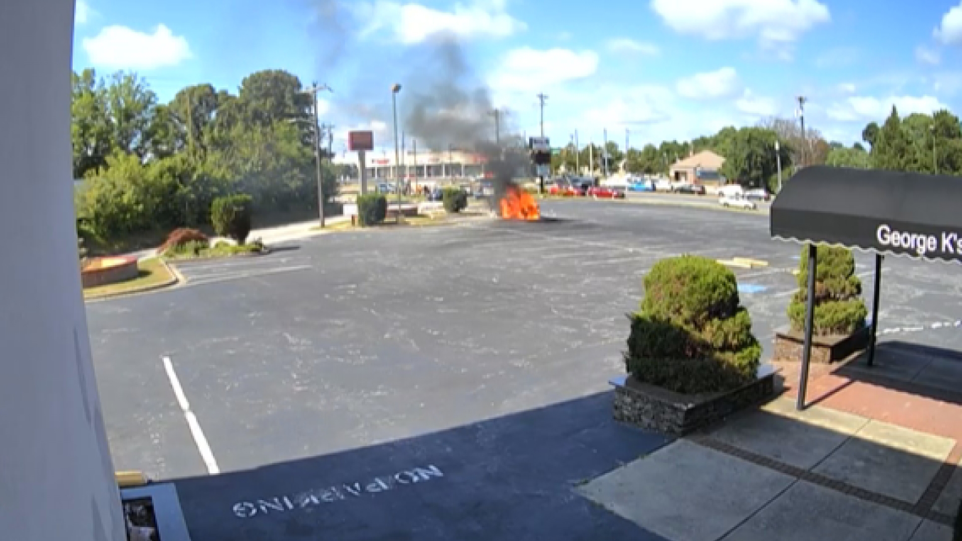 A car was scorched after it went flying into an ATM. A bystander stopped to help get the driver out, also caught on video.